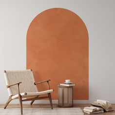 a chair and table in front of an orange wall with a book on the floor