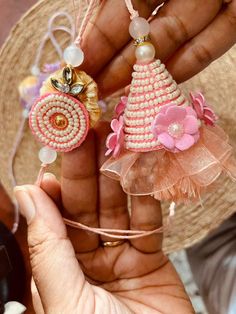 someone is holding two small pink and white earrings in their hands, one has a flower on it