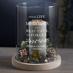 a memorial candle with succulents in it on a wooden base that reads, your life gave us memories too beautiful to forget