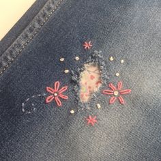 a pair of jeans with embroidered flowers on them