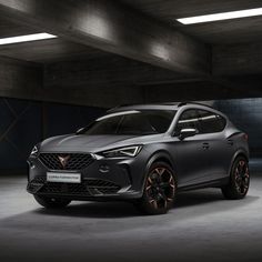 the front end of a blue suv parked in a garage with dark lighting and concrete flooring