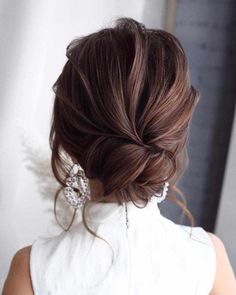 a woman with brown hair wearing a white dress and some big earrings on her head