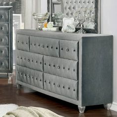 a silver dresser sitting in front of a mirror on top of a hard wood floor