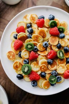 a white plate topped with pancakes covered in fruit