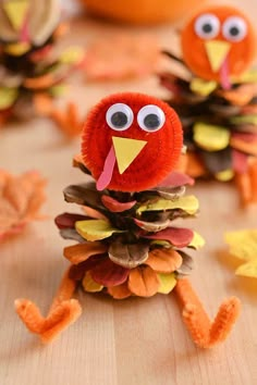 a turkey made out of pine cones on a table with leaves and pumpkins in the background