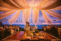 a bride and groom standing in front of their wedding reception table at the ocean side