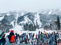 there are many skis and snowboards on the ground in front of a mountain