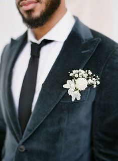 a man wearing a suit and tie with a boutonniere on his lapel