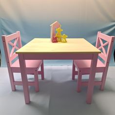 a wooden table with two chairs and a toy house on top