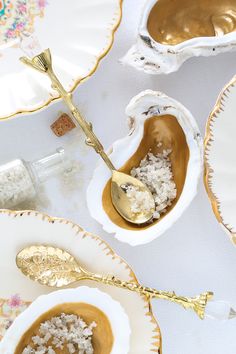 spoons and bowls filled with food sitting on top of white plates next to each other