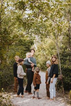 a group of people standing on top of a dirt road in front of some trees