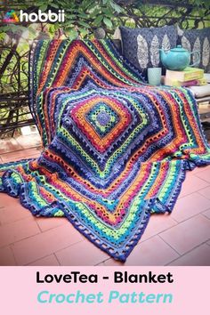 a crocheted blanket sitting on top of a wooden bench next to a potted plant