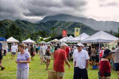 a group of people standing in the grass near tents with mountains in the back ground