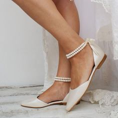 a woman wearing white shoes and pearls on her ankles