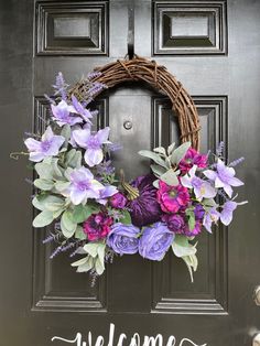 a welcome wreath with purple flowers and greenery