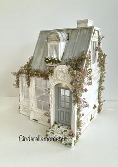 a doll house with flowers growing on the roof and windows above it is decorated in white