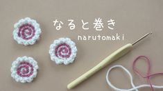 three crocheted flowers are next to a knitting needle