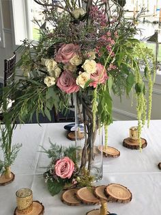 a vase filled with lots of flowers on top of a white table cloth covered table