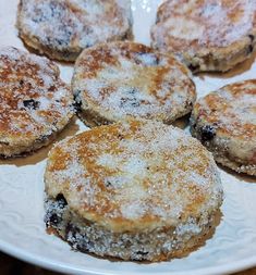 several small pastries on a white plate with powdered sugar and blueberry toppings