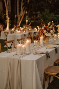 an outdoor dinner table with candles and flowers