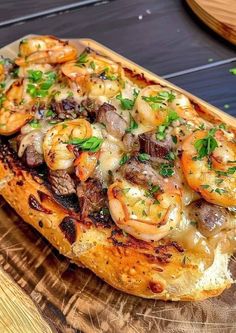 a wooden cutting board topped with shrimp and mushrooms on top of cheese covered pizza crust