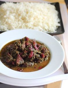 a white plate topped with meat and gravy next to rice