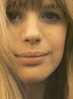 a close up of a woman with long blonde hair and bangs looking at the camera