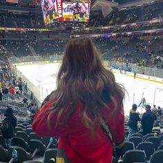 a woman standing in front of an ice hockey rink with her back to the camera