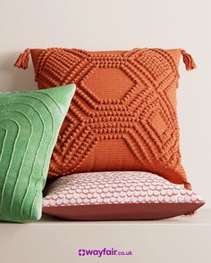 three pillows on a shelf with one green pillow and the other orange cushion, all in different colors