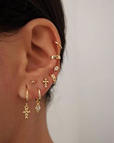 a woman wearing an ear cuff with cross and arrow designs on it's side