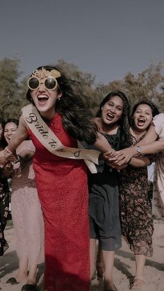 a group of women in dresses and sunglasses holding onto each other with their mouths open