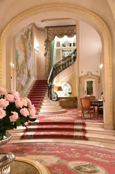 a vase with pink flowers sitting on top of a table next to a stair case