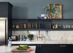 a kitchen with marble counter tops and black cabinets, along with wooden cutting boards on the wall