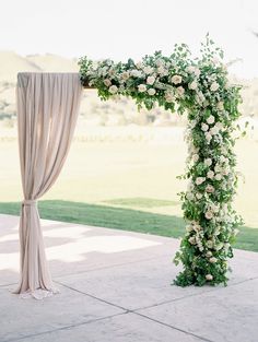 a wedding arch with white flowers and greenery