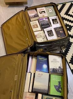 two open suitcases filled with books on the floor