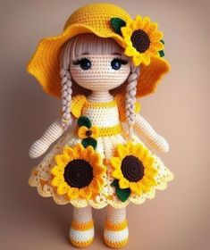 a crocheted doll with sunflowers on her dress and hat is posed in front of a brown background