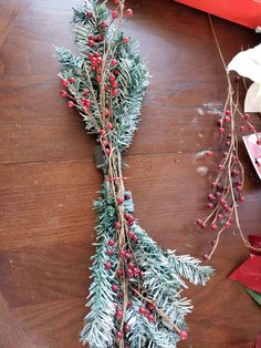 a bunch of branches with red berries on them sitting on a wooden floor next to other christmas decorations