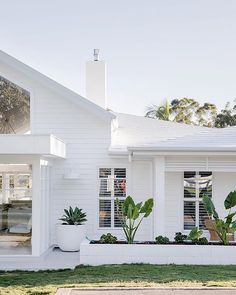 a white house with potted plants in the front yard