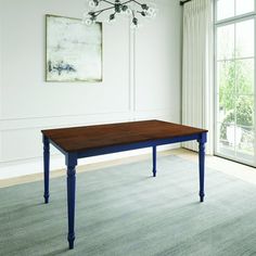 a dining room table with blue legs and a chandelier hanging from the ceiling