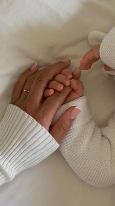 two people holding hands while laying in bed