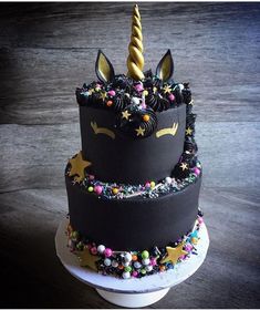 a three tiered cake decorated with black icing and rainbow sprinkles