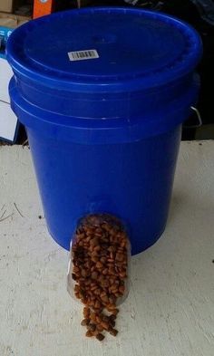 there is a blue bucket with some food in it on the floor next to a white table