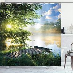 a bathroom with a shower curtain that has a view of the water and trees on it