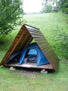 a blue tent sitting on top of a lush green field next to a wooden platform