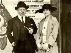 an old black and white photo of a man and woman in hats standing next to each other