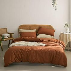 a bed with an orange comforter in a room next to a table and chair