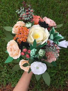 a bouquet of flowers is being held by someone's hand on the grass outside