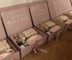 four pink boxes filled with different types of cakes and pastries on top of a wooden floor