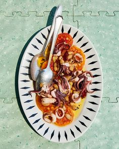 a white plate topped with lots of food on top of a green tablecloth next to a silver spoon