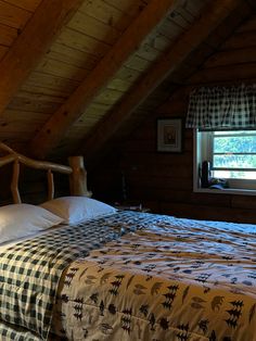 a bed in a room with wooden walls and ceiling beams, along with a checkered bedspread